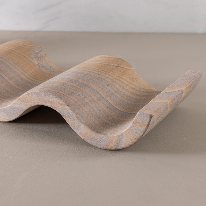 Close-up of a handcrafted rainbow sandstone wine rack, showcasing its wavy sculptural design and natural stone patterns.