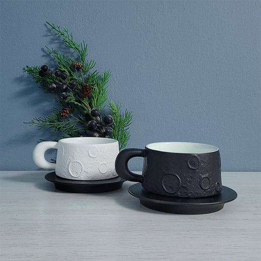 Black and white ceramic mugs on wood saucers – side by side